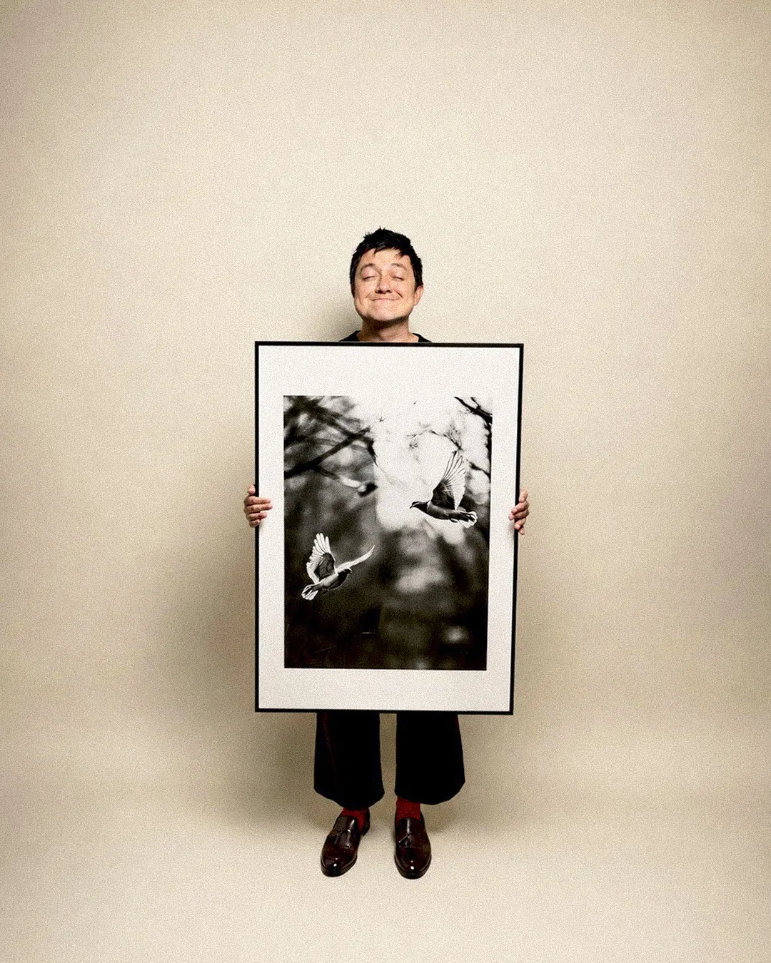 Lalo holding a framed black and white photograph of two birds in flight