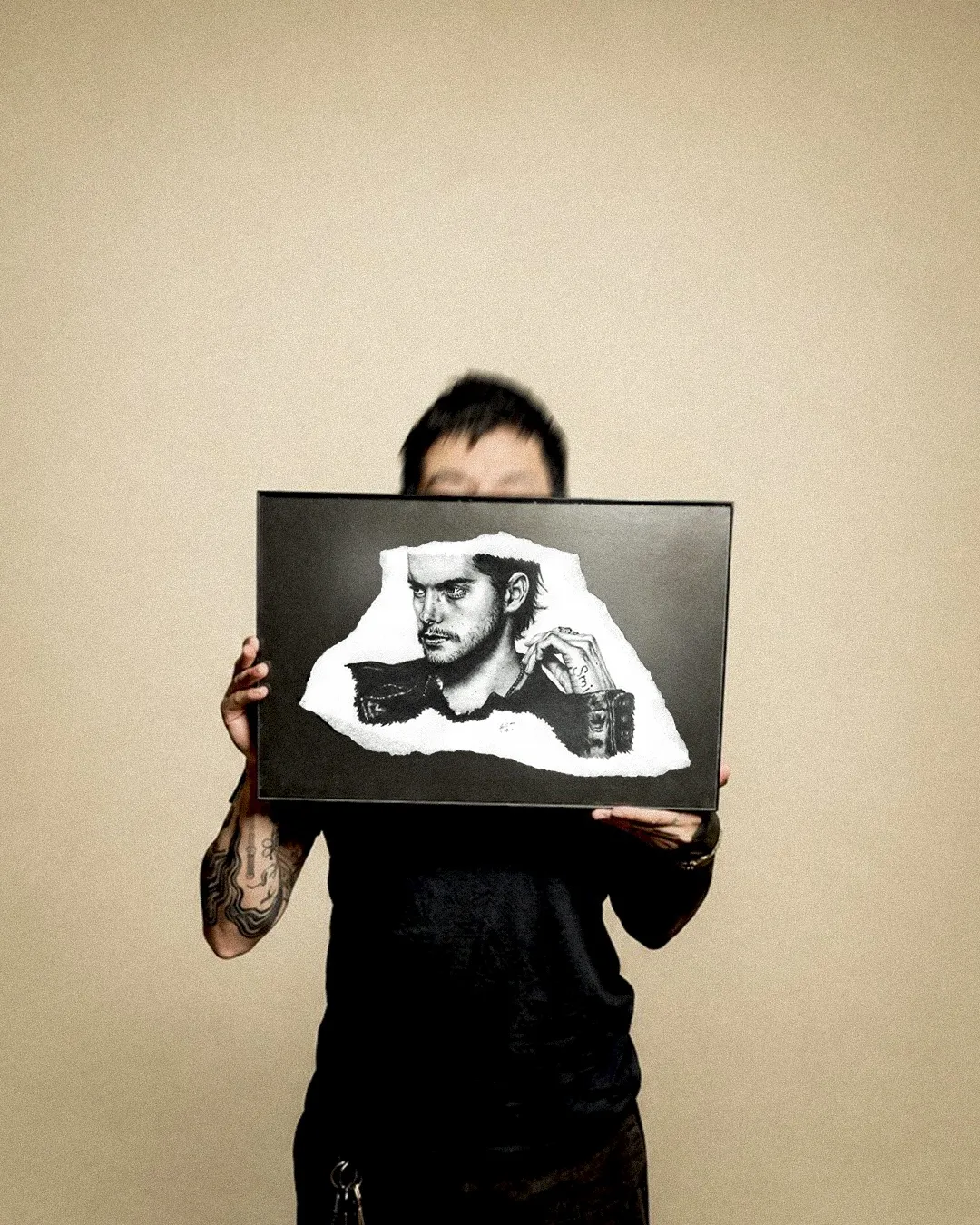 Lalo holding a framed black and grey portrait illustration