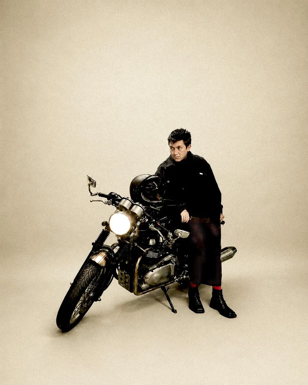 Lalo sitting on his cafe racer, looking at camera