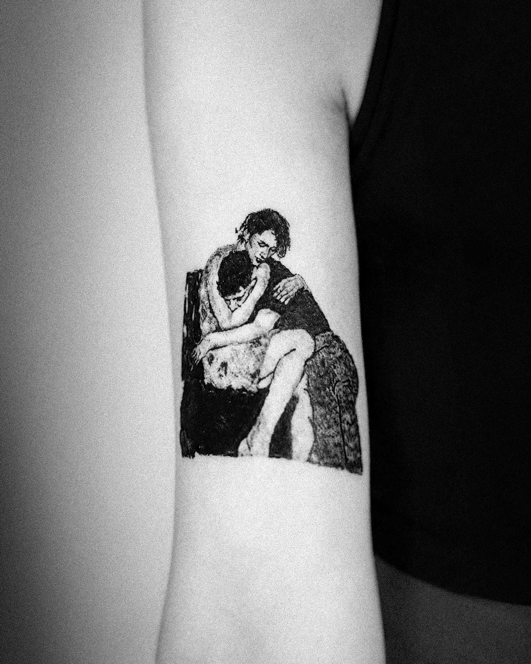 The embracing-figures tattoo photographed on the body