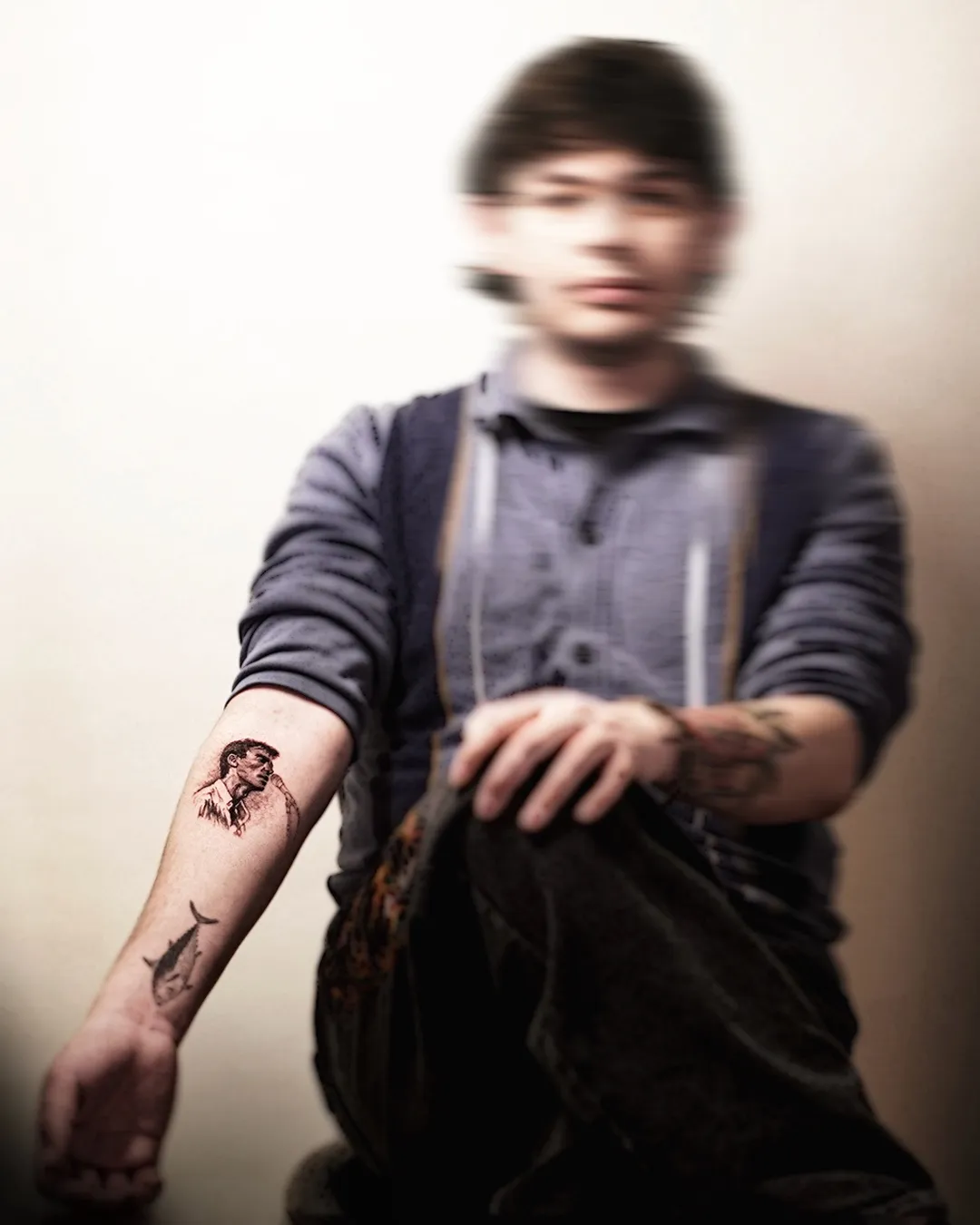 Fine black and grey micro-realism portrait with a small fish on the forearm